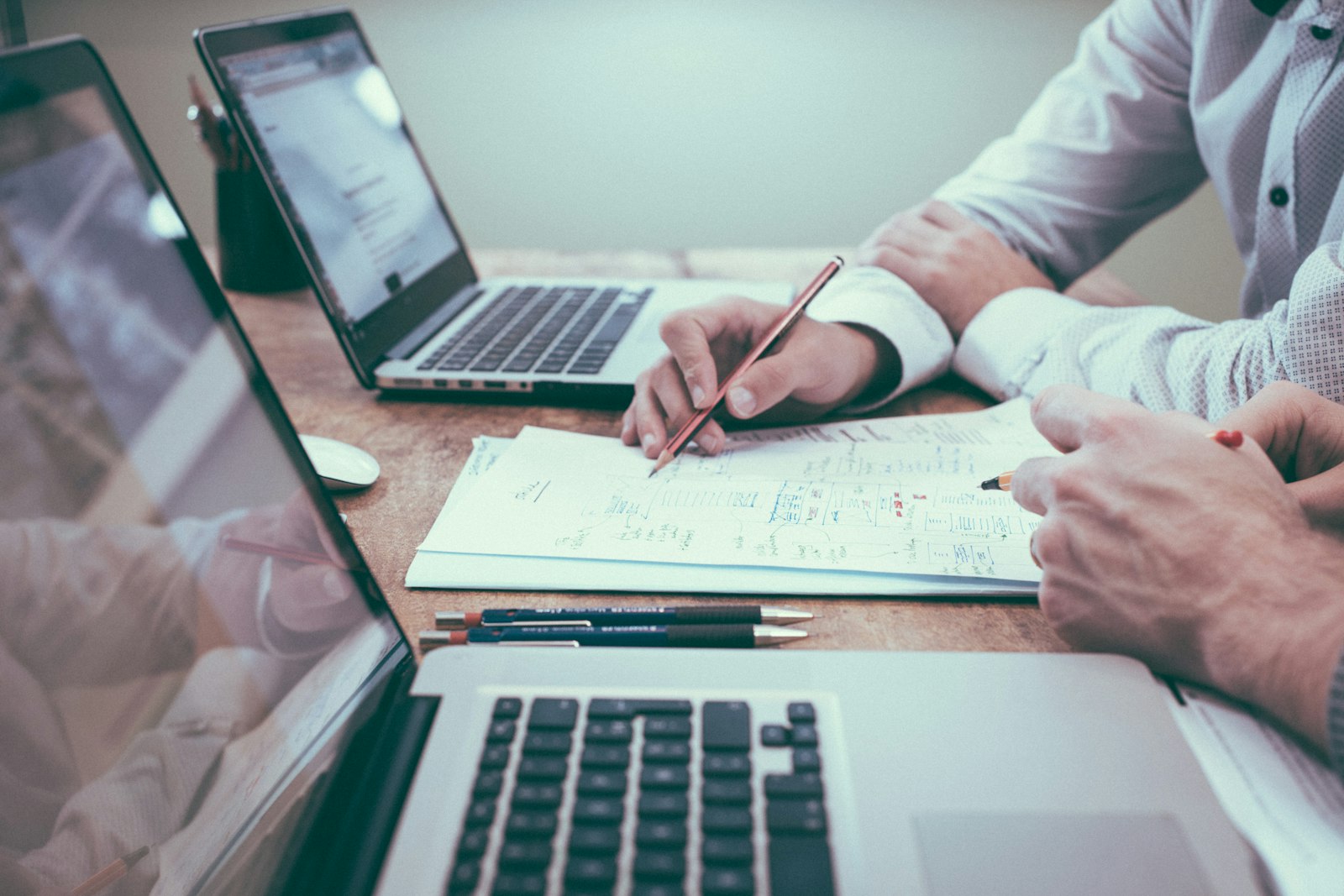 Laptops and printed reports spread across a planning table
